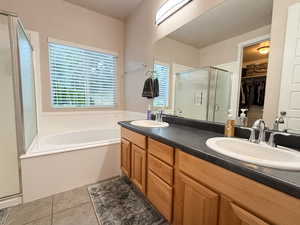 Bathroom with a shower stall, double vanity, a bath, tile patterned floors, and healthy amount of natural light