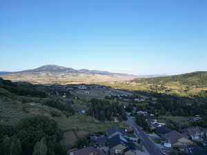 Aerial view of property and surrounding area featuring mountains and nearby suburban area