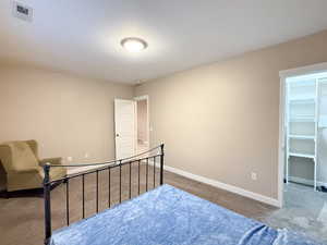 Carpeted bedroom with baseboards and a walk in closet
