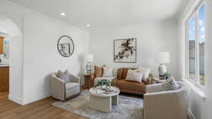 Living area with ornamental molding, light wood-style flooring, arched walkways, and recessed lighting