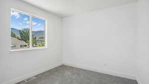 Carpeted empty room with baseboards and a mountain view
