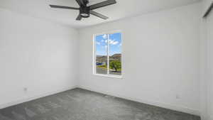 Spare room with dark carpet and ceiling fan