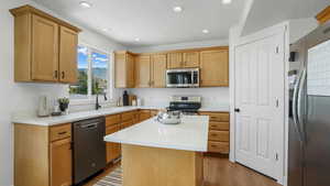Kitchen with stainless steel appliances, light countertops, recessed lighting, a textured ceiling, and light wood finished floors