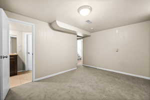 Finished below grade area with light colored carpet and stairway