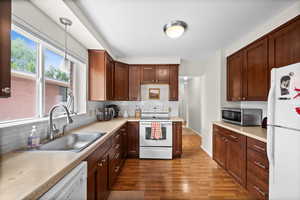 Kitchen with white appliances, wood finished floors, and backsplash