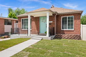 View of front of home featuring brick siding, roof with shingles, and a chimney