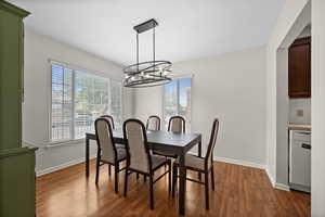 Dining space featuring a chandelier, healthy amount of natural light, and dark wood-style flooring