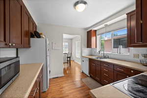 Kitchen featuring white appliances, light wood-style floors, backsplash, and healthy amount of natural light