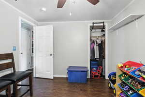 Bedroom with wood finished floors, a closet, ornamental molding, and a ceiling fan