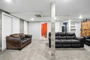 Carpeted living area with a barn door and recessed lighting