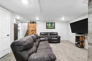 Carpeted living area featuring a barn door and recessed lighting