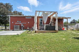 Back of house with a hot tub and a patio
