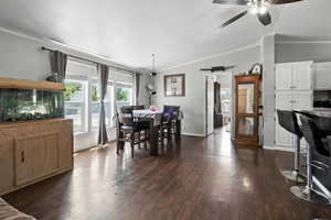 Dining room featuring vaulted ceiling, crown molding, a ceiling fan, and dark wood-type flooring