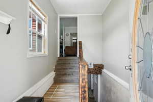 Stairs featuring wood finished floors and ornamental molding
