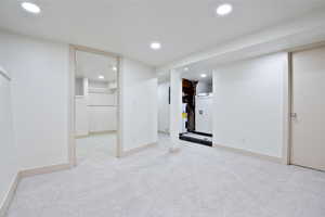 Finished basement featuring water heater, recessed lighting, and carpet