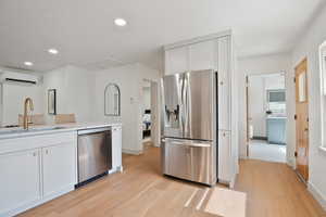Kitchen featuring stainless steel appliances, a wall mounted air conditioner, light wood finished floors, recessed lighting, and light countertops