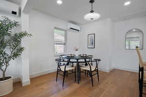Dining space with a wall mounted AC, light wood-style flooring, plenty of natural light, and recessed lighting