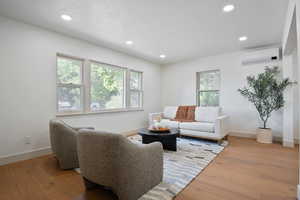 Living room with an AC wall unit, recessed lighting, and light wood finished floors