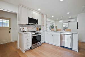 Kitchen featuring stainless steel appliances, a wall mounted AC, plenty of natural light, light wood finished floors, and recessed lighting