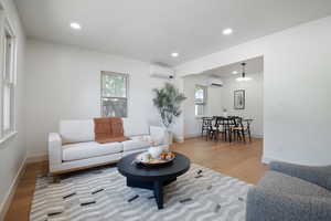 Living area featuring an AC wall unit, light wood-type flooring, and recessed lighting