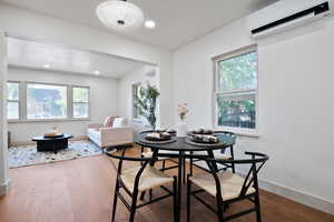 Dining area featuring a wall unit AC, wood finished floors, and recessed lighting