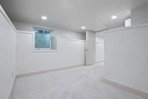 Finished basement with light colored carpet and recessed lighting