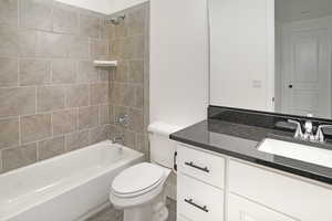 Second bathroom with quartz counters, steel tub, and full tile surround.