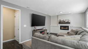 Living room with wood finished floors, a large fireplace, recessed lighting, and a textured ceiling