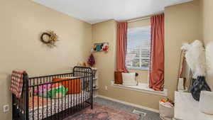 Carpeted bedroom featuring a nursery area and baseboards