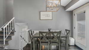 Dining area with a chandelier, wood finished floors, and stairs