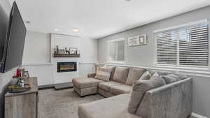 Living area featuring a glass covered fireplace, carpet, recessed lighting, and a textured ceiling