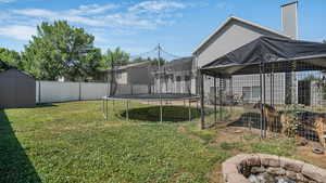 View of yard featuring a trampoline, an outdoor fire pit, and a storage shed