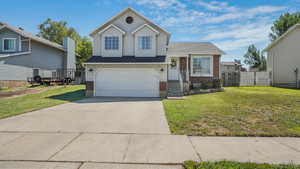 Tri-level home with brick siding, a garage, and driveway