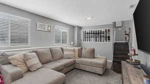 Carpeted living area with baseboards and a textured ceiling