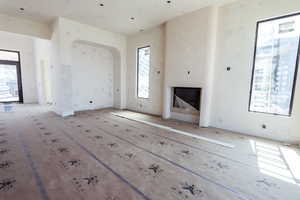 Unfurnished living room featuring arched walkways and a fireplace