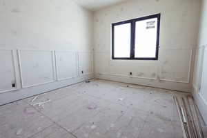 Empty room featuring a decorative wall and wainscoting