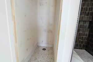 Bathroom with tile patterned floors and tiled shower