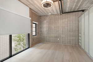 Empty room featuring wood finished floors and concrete block wall