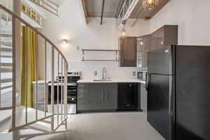 Kitchen with black appliances, gray cabinetry, finished concrete flooring, open shelves, and light countertops