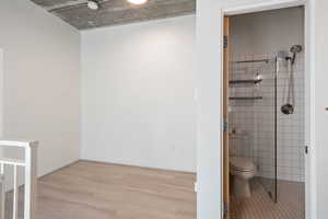 Bathroom with tile walls, wood finished floors, and tiled shower