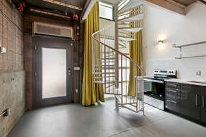 Kitchen with electric stove, finished concrete floors, and light countertops