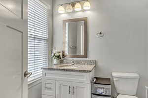 Bathroom with vanity, toilet, and plenty of natural light