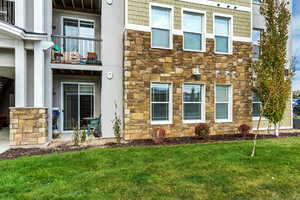 Property entrance with stone siding, a balcony, and a yard