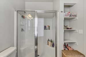 Full bath featuring toilet and a stall shower