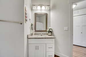 Bathroom featuring vanity, wood finished floors, and baseboards