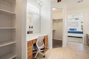 Primary Bathroom featuring built in desk, light carpet, light tile patterned flooring, and a ceiling fan
