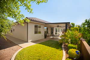 Back of house featuring a ceiling fan, a lawn, a patio, a tile roof, and stucco siding