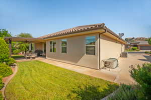 Rear view of property featuring a yard, a ceiling fan, a patio area, a tiled roof, and stucco siding