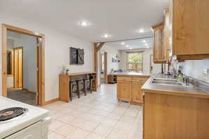 Kitchen featuring stove, recessed lighting, light tile patterned floors, a peninsula, and light countertops
