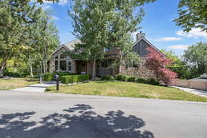 View of front of home with a chimney, stone siding, and a front yard